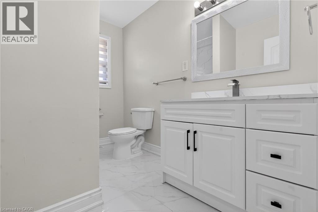 White vanity with black hardware, a rectangular mirror, and a modern single-handle faucet, set against light-toned walls and marble-look floor tiling - 53 Nicklin Crescent, Guelph, ON - Indoor Photo Showing Bathroom