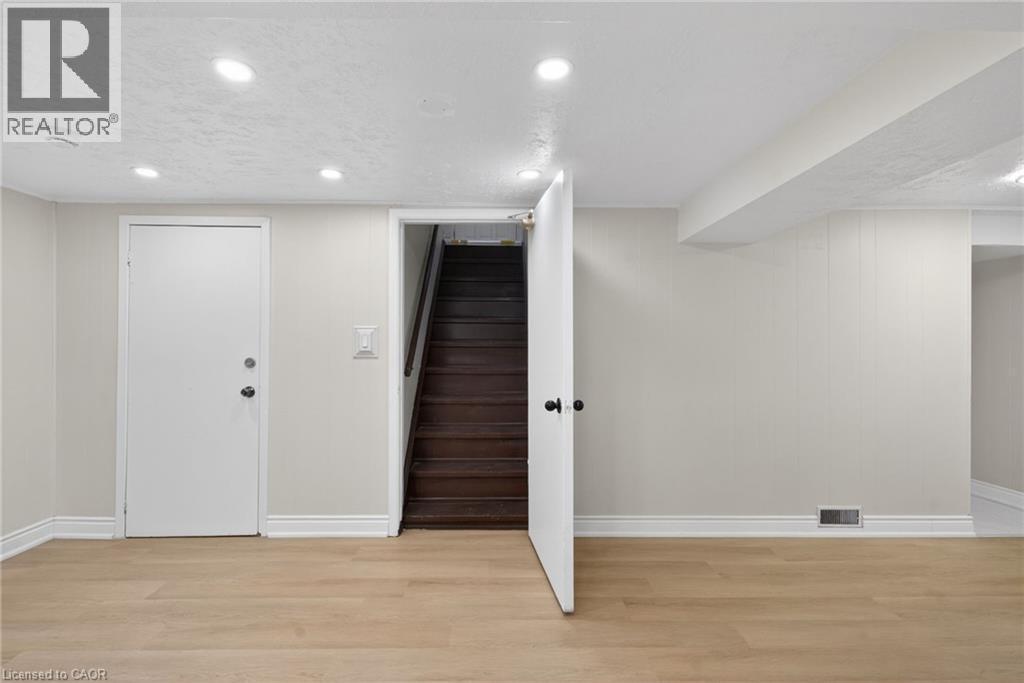 Spacious room featuring wood-finish flooring, recessed lighting, and crisp white trim - 53 Nicklin Crescent, Guelph, ON - Indoor