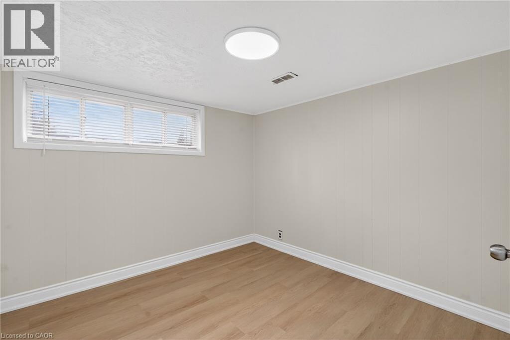 Room featuring wood-finish flooring, a rectangular window with blinds, and a flush-mount ceiling light - 53 Nicklin Crescent, Guelph, ON - Indoor Photo Showing Other Room