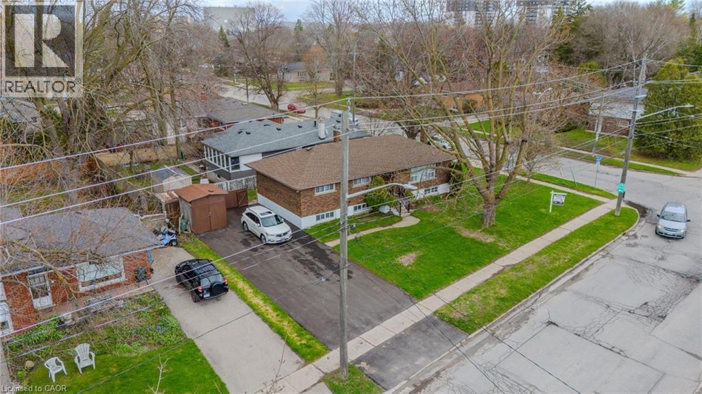 Brown brick exterior featuring a brown shingle roof, established front lawn, paved driveway, and detached storage sheds - 53 Nicklin Crescent, Guelph, ON - Outdoor