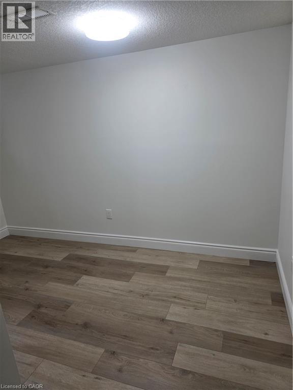 Room featuring wood-finish flooring, white baseboards, light neutral wall paint, and a flush-mount ceiling light - 22 Montrose Avenue, Kitchener, ON - Indoor Photo Showing Other Room