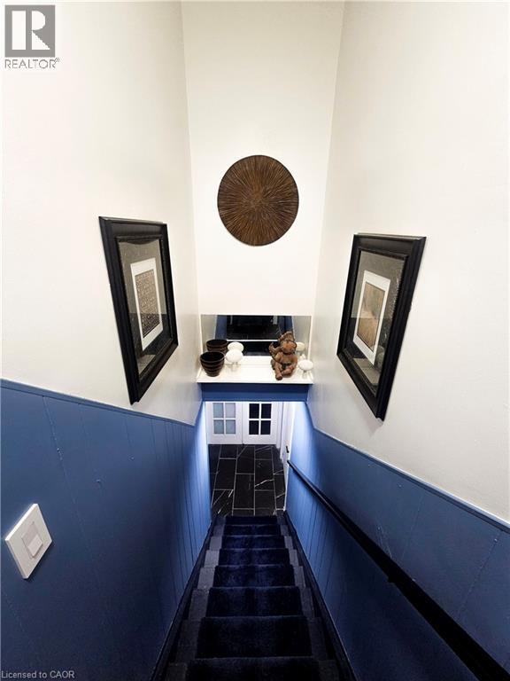 Staircase featuring dark blue carpeted treads and wainscoting - 34 Christopher Drive, Cambridge, ON - Indoor