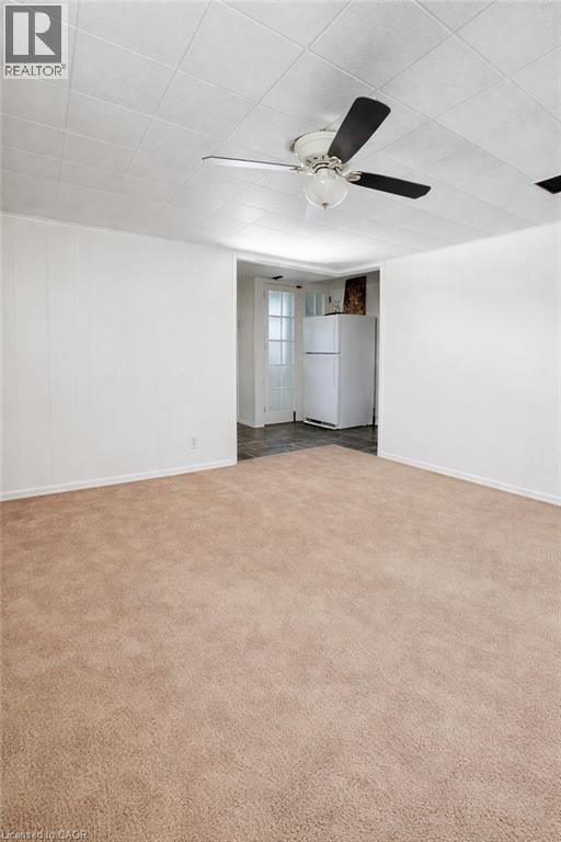 Spacious carpeted room featuring a ceiling fan with integrated lighting, white panel walls, and a dropped ceiling - 34 Christopher Drive, Cambridge, ON - Indoor Photo Showing Other Room