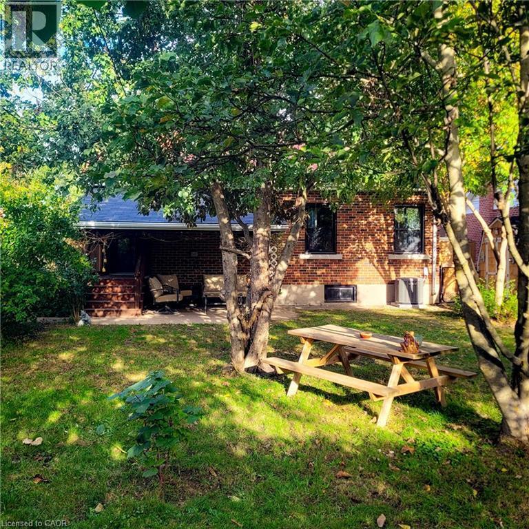 Brick exterior residence featuring a covered patio, a manicured lawn, and mature trees providing natural shade - 34 Christopher Drive, Cambridge, ON - Outdoor