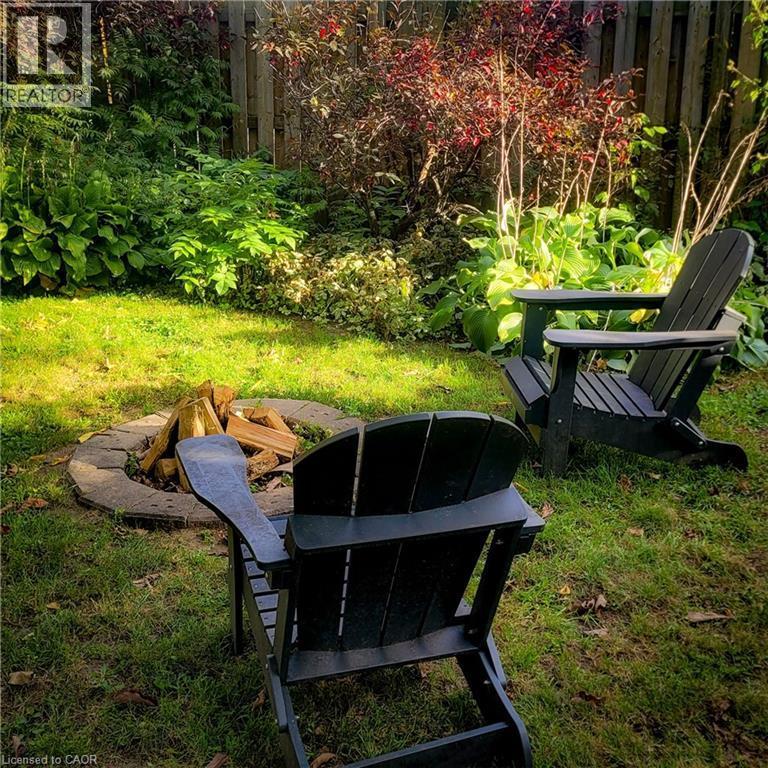 Backyard featuring a stone fire pit, green lawn, and varied mature landscaping - 34 Christopher Drive, Cambridge, ON - Outdoor