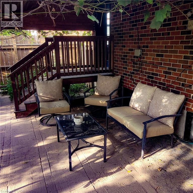 Covered outdoor patio featuring a wood-finish deck and brick exterior wall - 34 Christopher Drive, Cambridge, ON - Outdoor With Deck Patio Veranda With Exterior