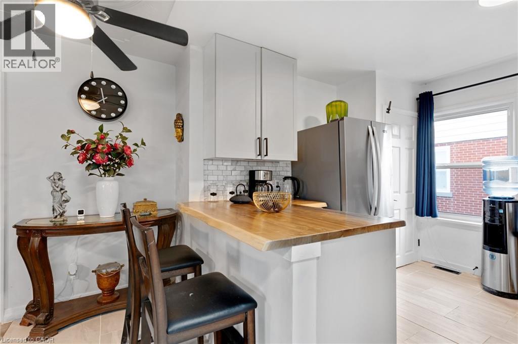 Kitchen featuring a natural wood-finish countertop, white cabinetry with dark hardware, white subway tile backsplash, and light wood-finish flooring - 34 Christopher Drive, Cambridge, ON - Indoor Photo Showing Kitchen