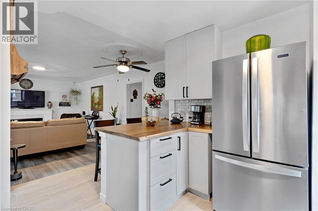 Kitchen featuring wood-finish countertops, white shaker cabinetry with black hardware, and a subway tile backsplash - 34 Christopher Drive, Cambridge, ON - Indoor Photo Showing Kitchen