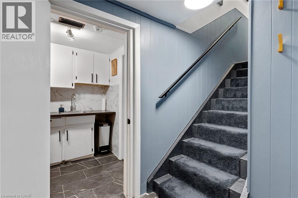 Carpeted staircase with dark handrail and light blue vertical plank paneling - 34 Christopher Drive, Cambridge, ON - Indoor Photo Showing Other Room