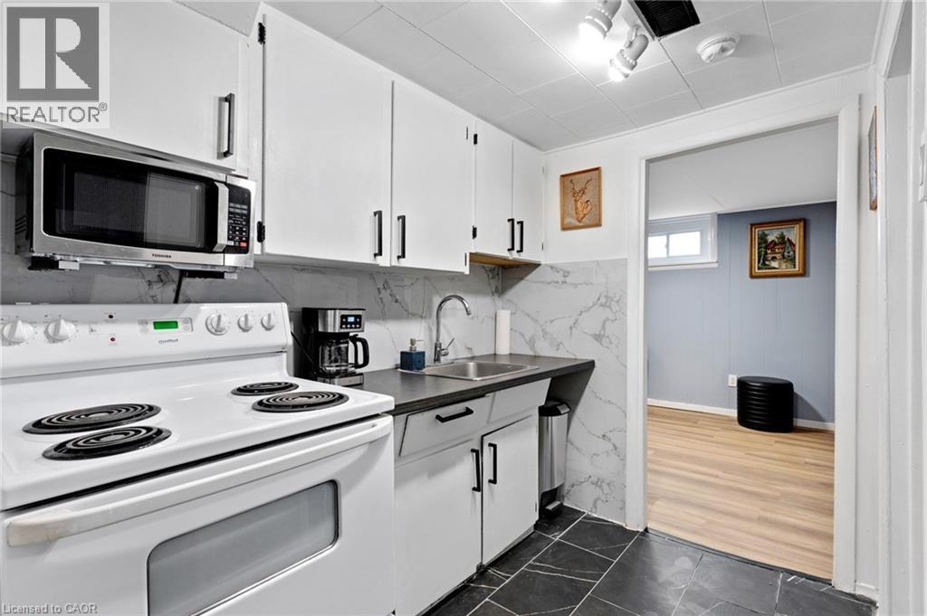 Kitchen featuring white cabinetry with dark pulls, dark countertops, and a white electric range - 34 Christopher Drive, Cambridge, ON - Indoor Photo Showing Kitchen
