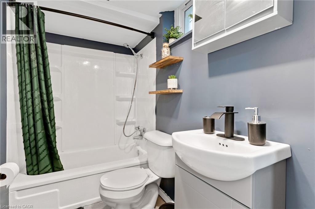 Bathroom featuring a pedestal sink with dark-toned fixtures, a wall-mounted medicine cabinet, and a white tub with an integrated showerhead - 34 Christopher Drive, Cambridge, ON - Indoor Photo Showing Bathroom