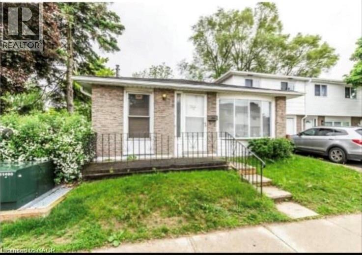 Brick facade residence featuring a front porch with wrought iron railing, a prominent bay window, and a sloped grass lawn - 744 Parkview Crescent, Cambridge, ON - Outdoor