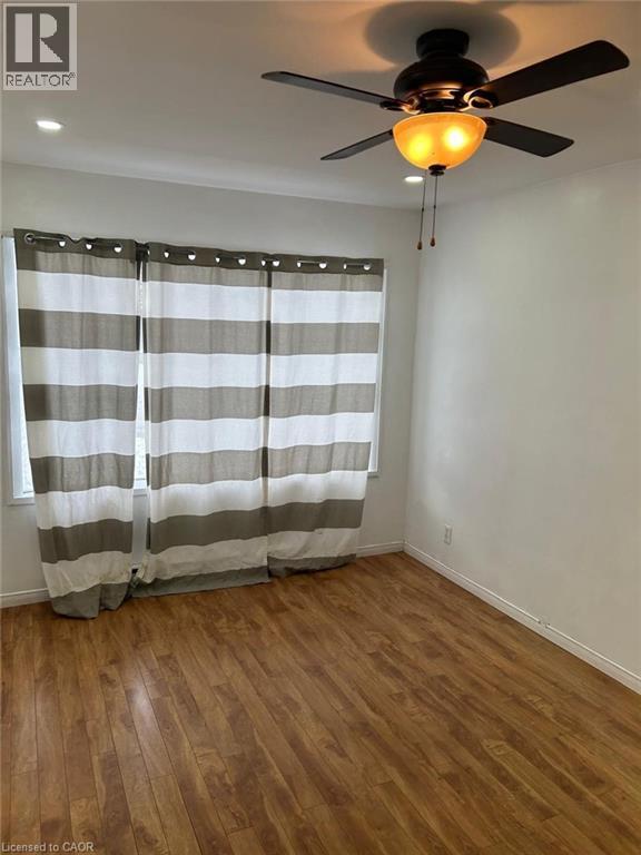 Bright interior space featuring wood-finish flooring, a window with horizontal striped drapes, a ceiling fan with integrated lighting, and recessed ceiling lights - 744 Parkview Crescent, Cambridge, ON - Indoor Photo Showing Other Room
