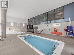 Indoor aquatic facility featuring a swim spa, a hot tub, tiled flooring, high ceilings, and expansive windows -