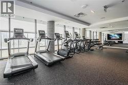 Fitness center featuring cardio equipment, strength training machines, free weights, a large display screen, and resilient rubber flooring -