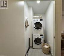 Dedicated laundry closet featuring a stacked washer and dryer, recessed lighting, and tile flooring -