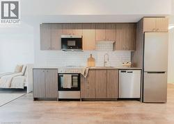 Modern kitchen featuring a full suite of stainless steel appliances, wood-finish cabinetry, white subway tile backsplash, and light-tone countertops -