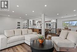 Open-concept living space featuring wood-finish flooring, recessed lighting, and white walls - 