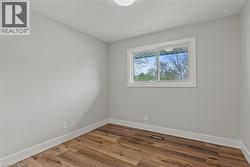 Bright room with wood-finish flooring, light grey painted walls, white trim, and a rectangular window - 