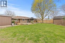 Expansive backyard featuring a manicured lawn, a large wood deck, and a wooden privacy fence - 