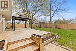 Expansive wooden deck featuring a gazebo, built-in planters, and steps to a stone paver path - 