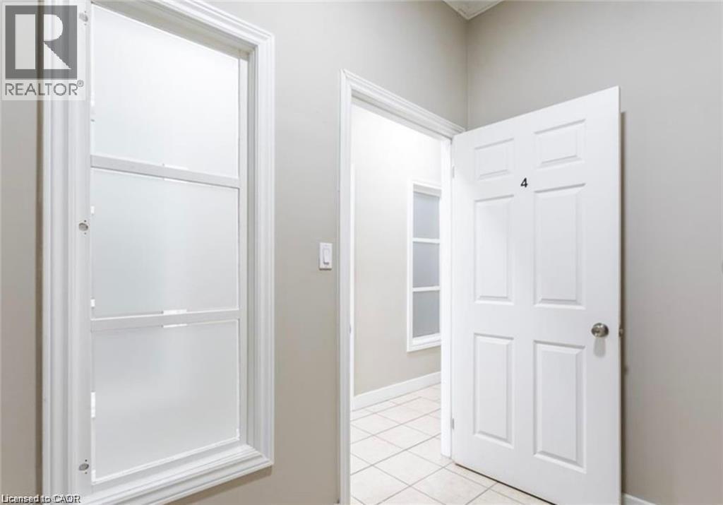 The property features a white paneled door with a silver-tone doorknob, and windows with white frames - 833 King Street E, Hamilton, ON