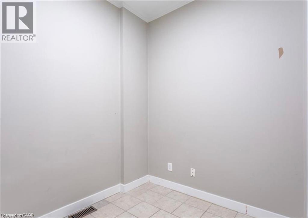 This room features light-colored walls, white baseboards, and tiled flooring - 833 King Street E, Hamilton, ON