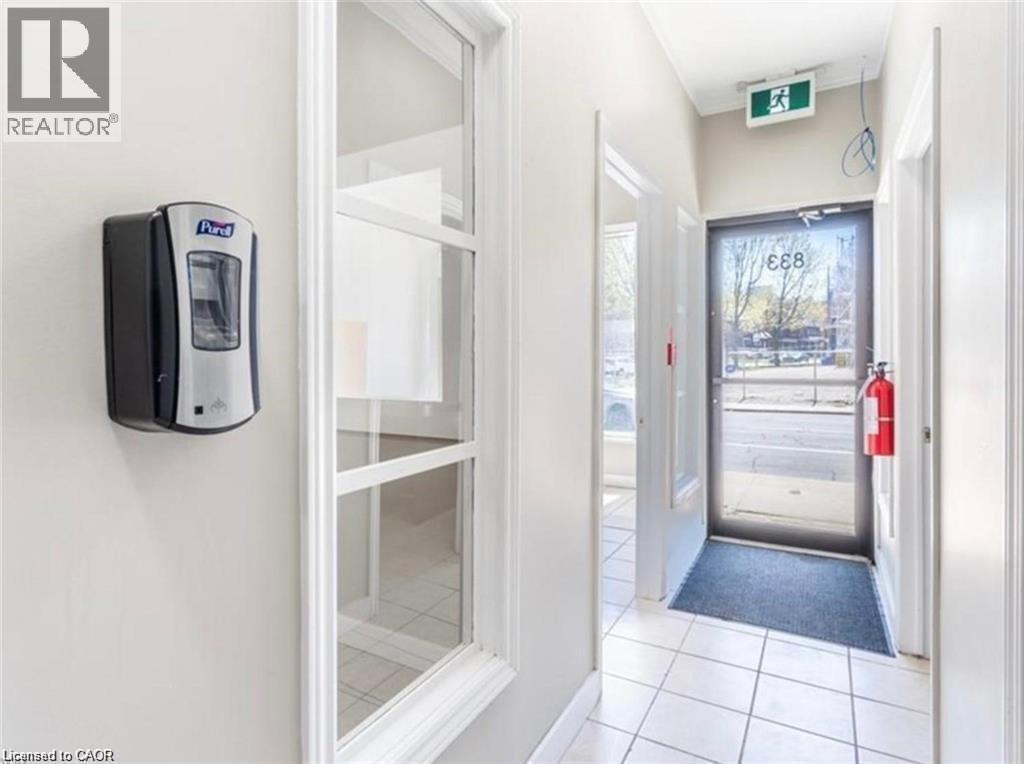 Entryway featuring white tile flooring, a glass panel door, and white walls - 833 King Street E, Hamilton, ON