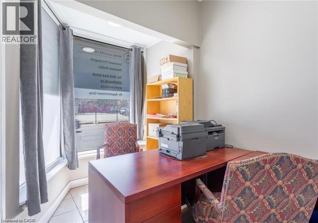 This well-lit office space features a large window, providing natural light, and tiled flooring - 833 King Street E, Hamilton, ON