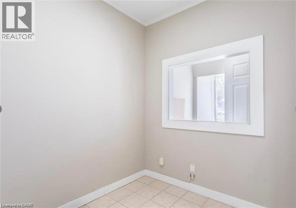 This room features tiled flooring and light-colored walls, complemented by a prominent white-framed mirror - 833 King Street E, Hamilton, ON