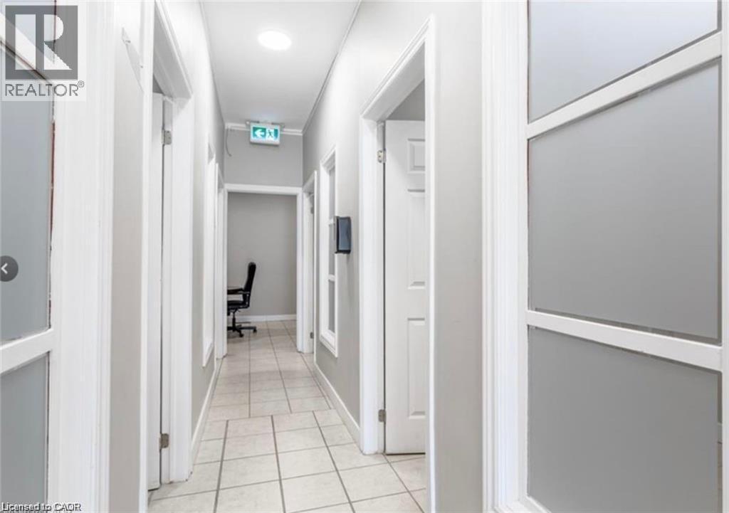 The property features a well-lit hallway with tiled flooring and recessed lighting - 833 King Street E, Hamilton, ON