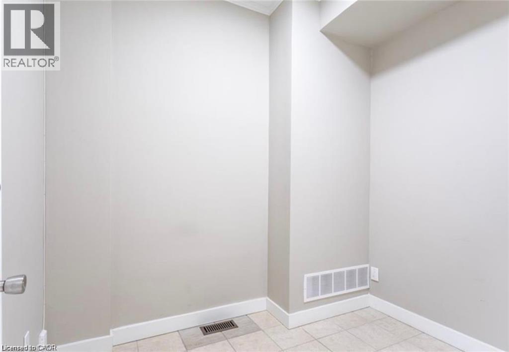 This area features light-colored walls, white baseboards, and tiled flooring - 833 King Street E, Hamilton, ON
