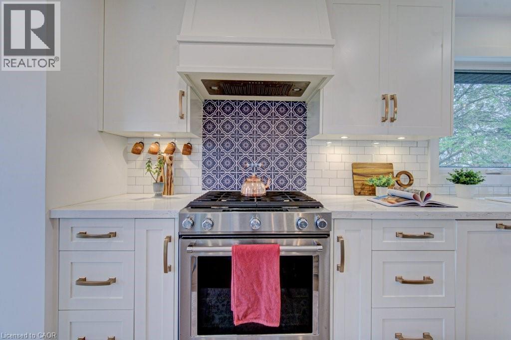 Kitchen featuring a stainless steel range with a custom range hood, white shaker-style cabinetry, and light-toned countertops - 1486 Augustine Drive, Burlington, ON - Indoor Photo Showing Kitchen