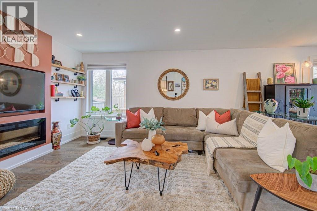Open concept living area featuring wood-finish flooring, a built-in fireplace, and a large window - 1486 Augustine Drive, Burlington, ON - Indoor Photo Showing Living Room With Fireplace