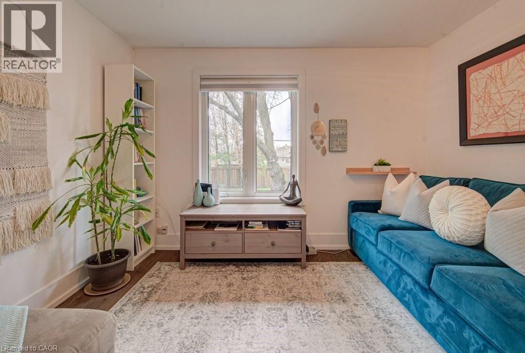 Bright living space featuring wood-finish flooring, a large window, a built-in bookshelf, a floating shelf, and a framed wall art piece - 1486 Augustine Drive, Burlington, ON - Indoor Photo Showing Living Room
