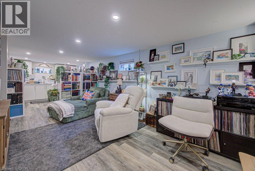 Finished basement featuring wood-finish flooring, recessed lighting, and a built-in wet bar with white cabinetry and a subway tile backsplash - 1486 Augustine Drive, Burlington, ON - Indoor