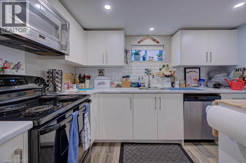 Kitchen featuring white cabinetry, subway tile backsplash, recessed lighting, wood-finish flooring, and a stainless steel dishwasher - 1486 Augustine Drive, Burlington, ON - Indoor Photo Showing Kitchen