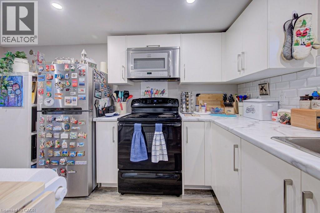 Well-appointed kitchen featuring white cabinetry, light-toned countertops, and a subway tile backsplash - 1486 Augustine Drive, Burlington, ON - Indoor Photo Showing Kitchen