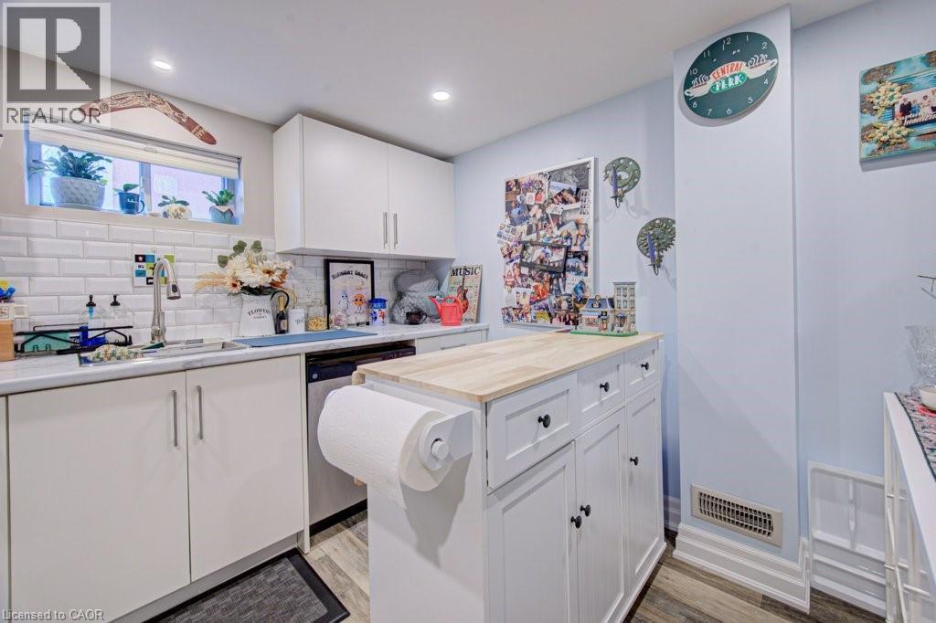 Contemporary kitchen featuring white cabinetry, subway tile backsplash, a stainless steel sink, recessed lighting, and wood-finish flooring - 1486 Augustine Drive, Burlington, ON - Indoor Photo Showing Kitchen