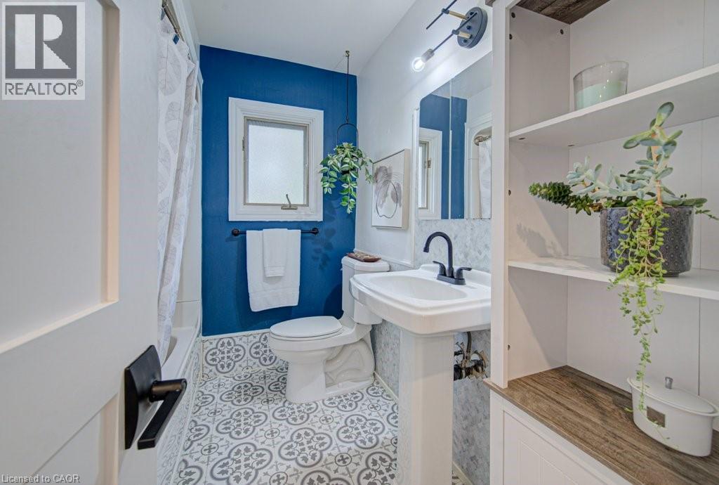 Bathroom featuring patterned floor tiles, a pedestal sink with a matte black faucet, and built-in shelving with wood-finish accents - 1486 Augustine Drive, Burlington, ON - Indoor Photo Showing Bathroom