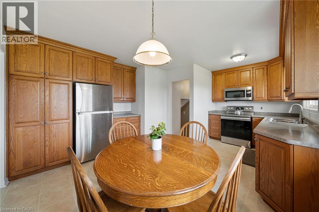 Kitchen featuring extensive wood cabinetry, stainless steel appliances, and a tile flooring - 2223 Hall Road, Binbrook, ON - Indoor