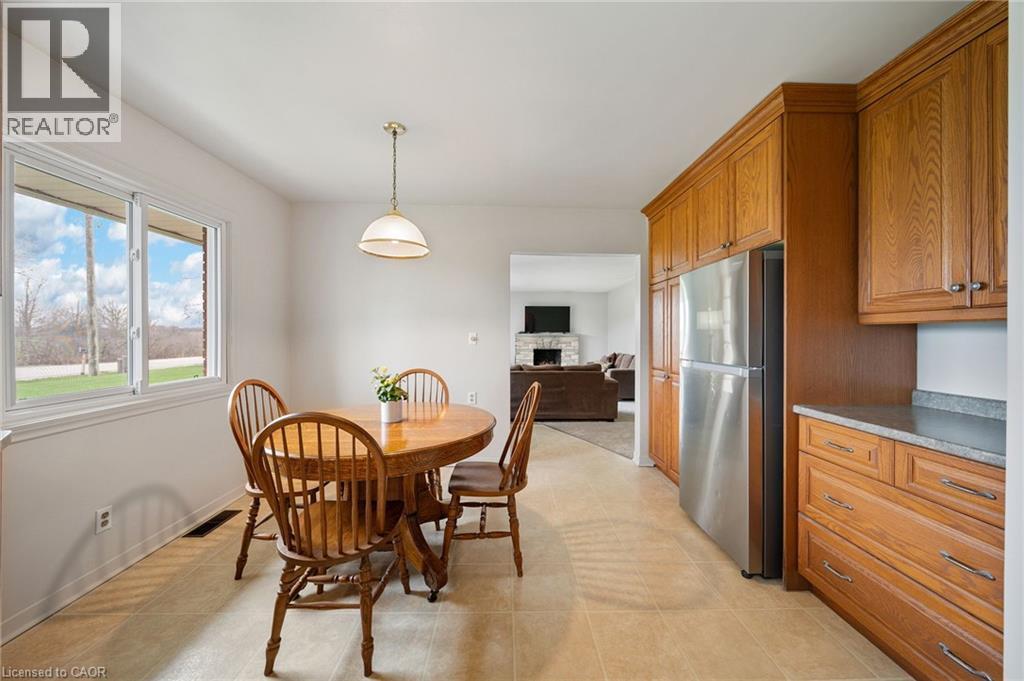 Kitchen area featuring natural wood cabinetry, stainless steel refrigerator, and tiled flooring - 2223 Hall Road, Binbrook, ON - Indoor Photo Showing Dining Room