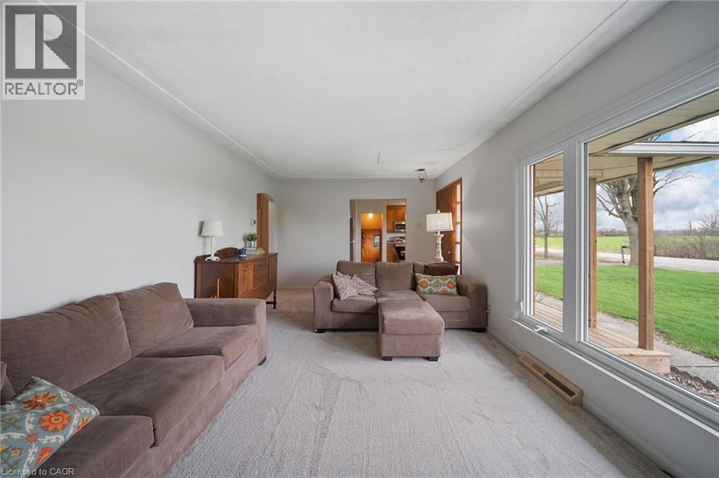 Light-filled room featuring a large picture window, light gray carpeting, and white painted walls - 2223 Hall Road, Binbrook, ON - Indoor Photo Showing Living Room