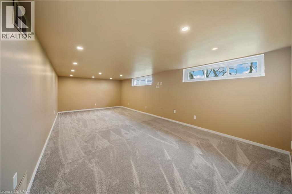 Spacious room featuring light-toned carpeting, recessed ceiling lighting, and multiple egress windows - 2223 Hall Road, Binbrook, ON - Indoor Photo Showing Other Room