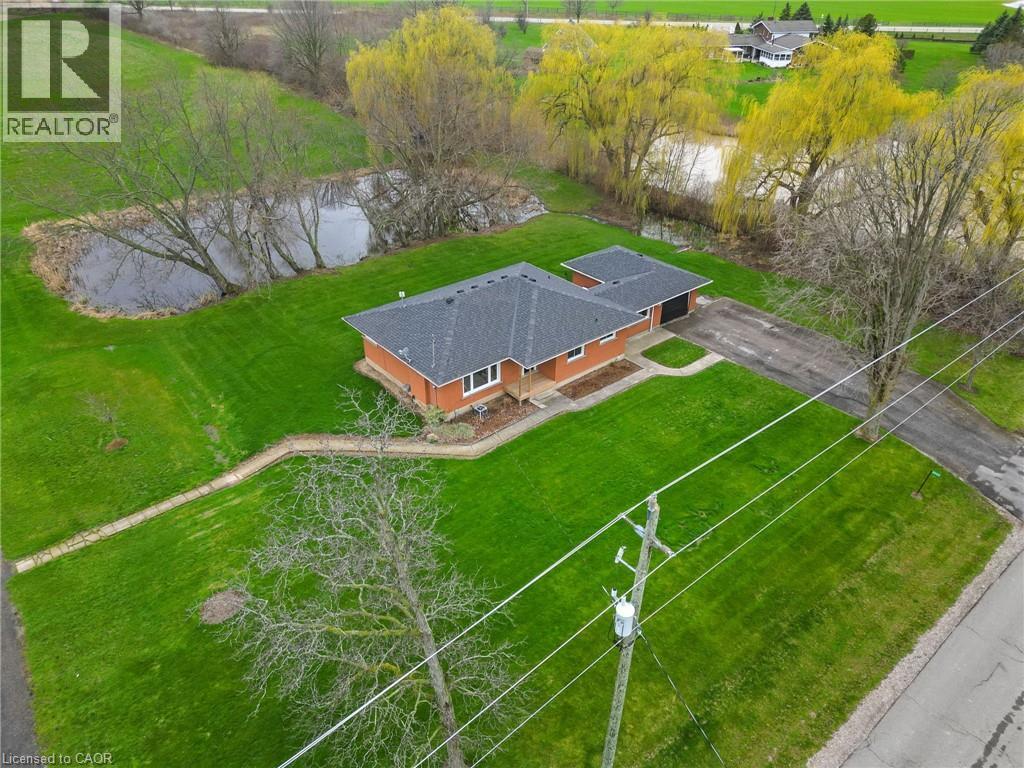 Brick exterior home featuring an attached garage, a paved driveway, a dark shingled roof, and a private pond - 2223 Hall Road, Binbrook, ON - Outdoor