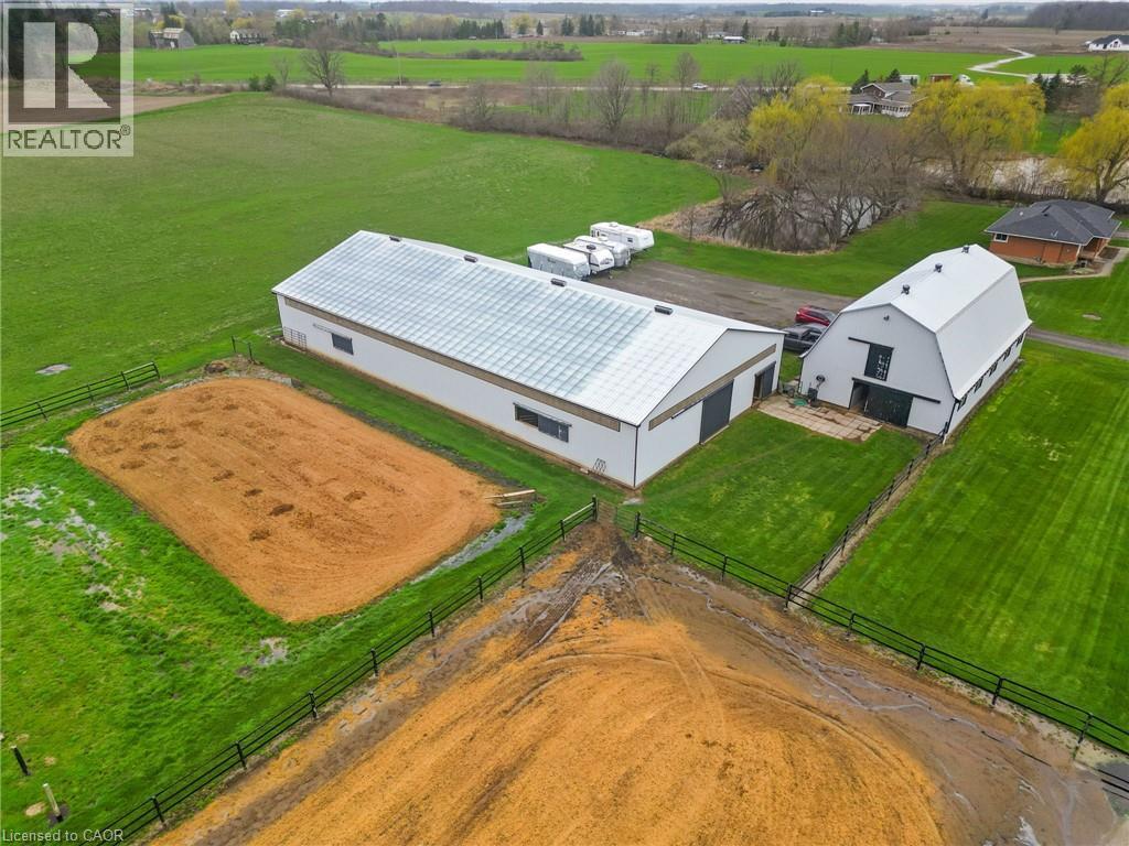 Expansive rural property featuring two white modern barns with gabled roofs, surrounded by manicured green lawns and fenced paddocks - 2223 Hall Road, Binbrook, ON - Outdoor With View