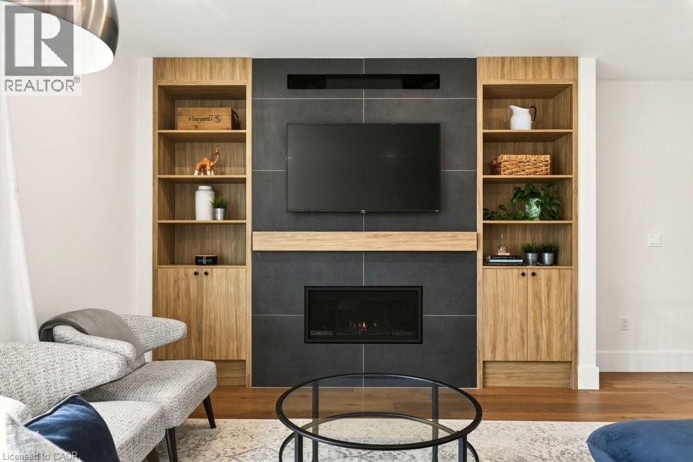 Built-in media center featuring a dark tile surround fireplace with a wood mantel - 128 Canada Street, Hamilton, ON - Indoor Photo Showing Living Room