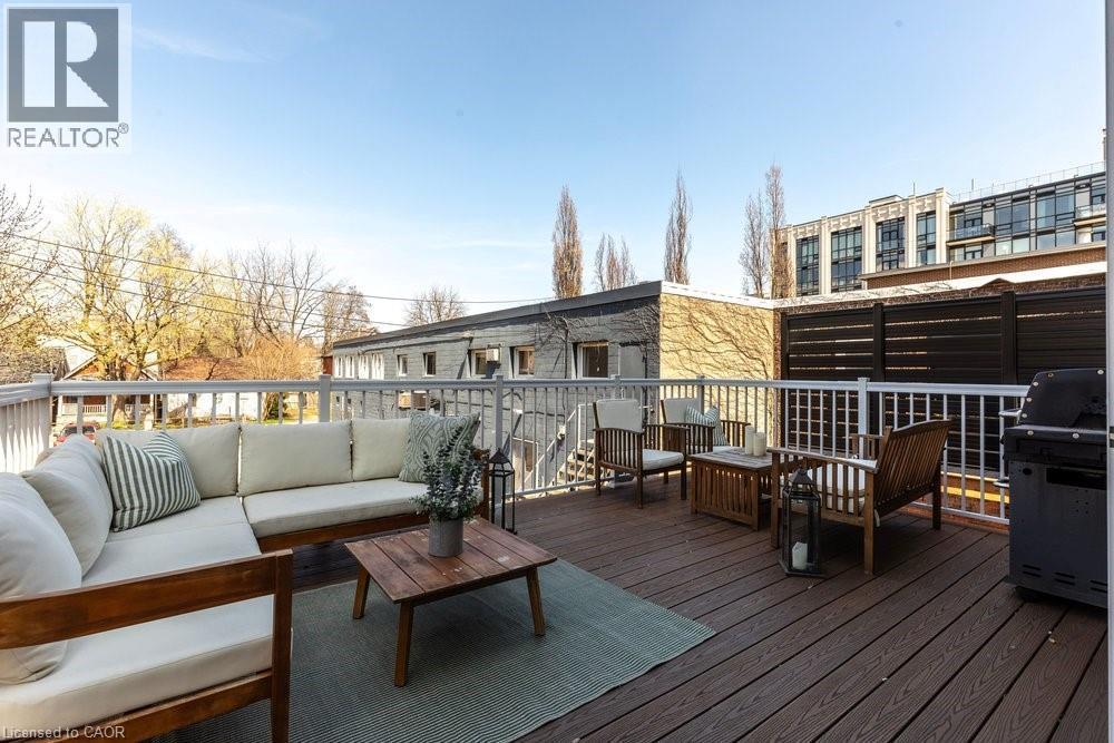 Spacious outdoor deck featuring composite decking, white railing, privacy screen, and exterior lighting - 128 Canada Street, Hamilton, ON - Outdoor With Deck Patio Veranda With Exterior