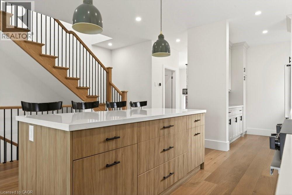 Kitchen island featuring a light wood-finish base, white countertop, and dark hardware - 128 Canada Street, Hamilton, ON - Indoor Photo Showing Other Room