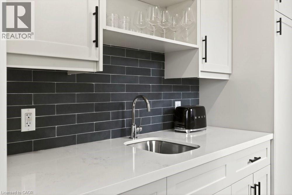 White shaker cabinetry with matte black hardware, a dark subway tile backsplash, a stainless steel undermount sink, and a chrome faucet - 128 Canada Street, Hamilton, ON - Indoor Photo Showing Kitchen